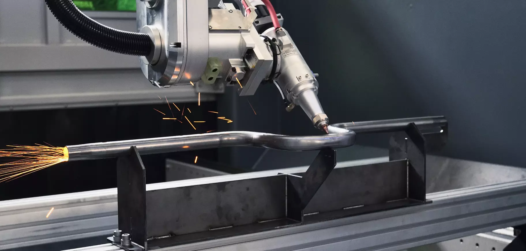 Five-axis laser cutting a bent metal tube held in a fixture